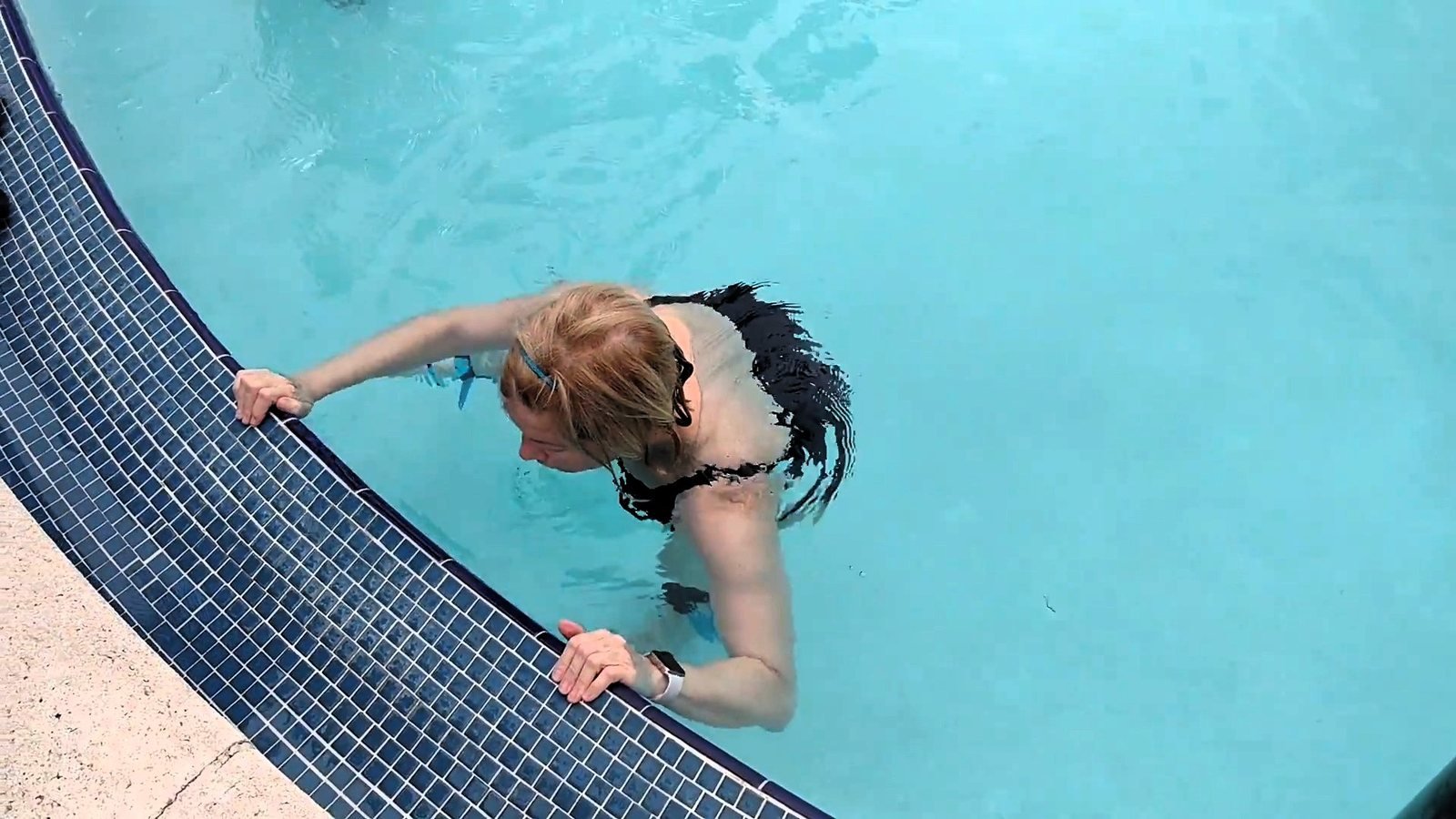 Woman exercising at the edge of her private backyard pool.