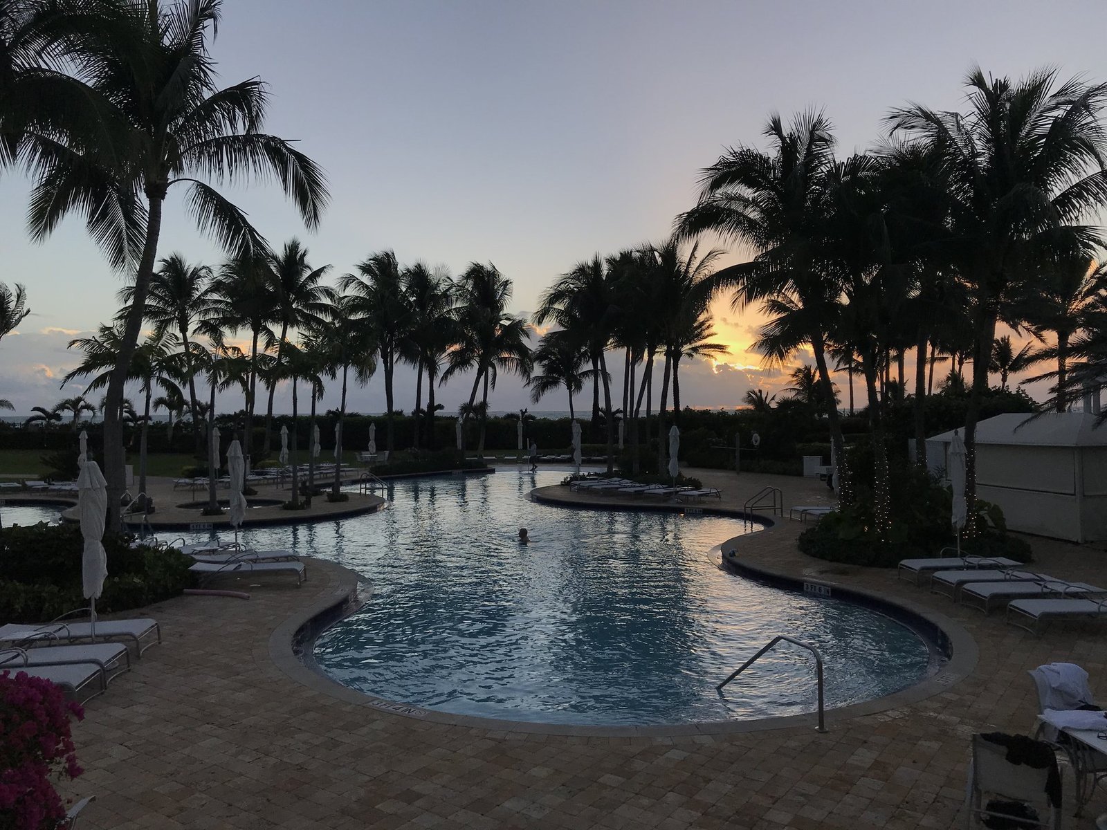 A swimmer in a shaded condominium pool at sunrise.