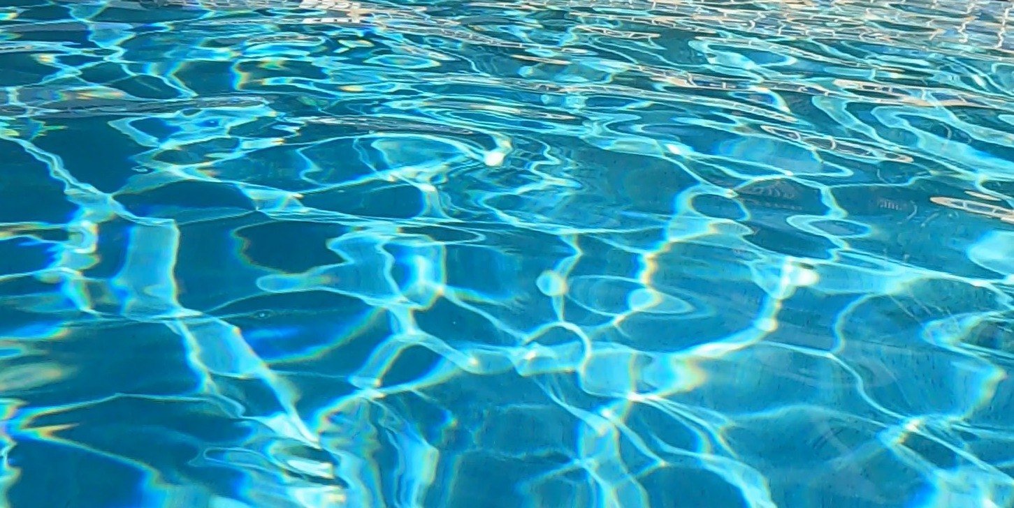 Sunlight moving across clear blue pool water.