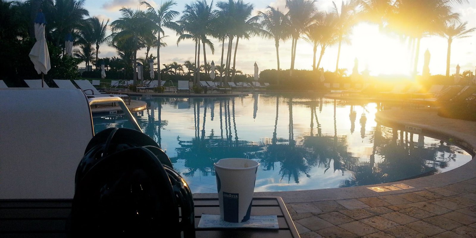 A double espresso on a poolside table at sunrise