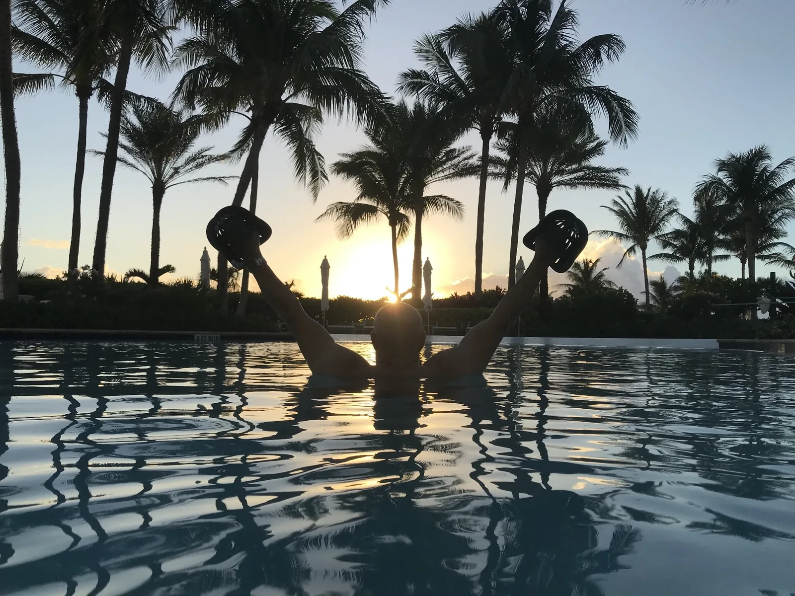 AquaFit Sports resistance bell training at sunrise in a luxury pool setting